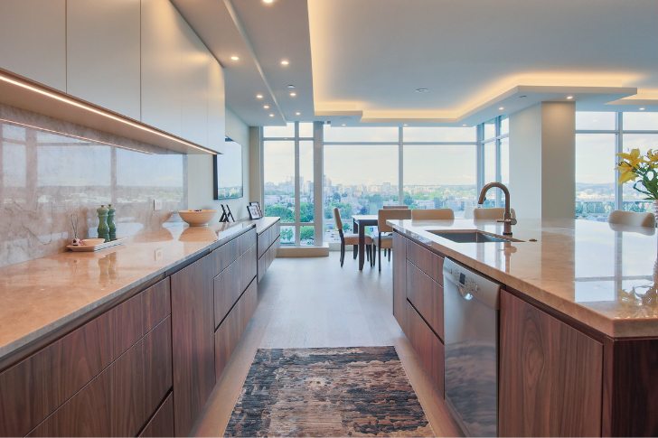 Kitchen renovation with wooden cabinets and modern lighting with a beautiful view through floor to ceiling windows.